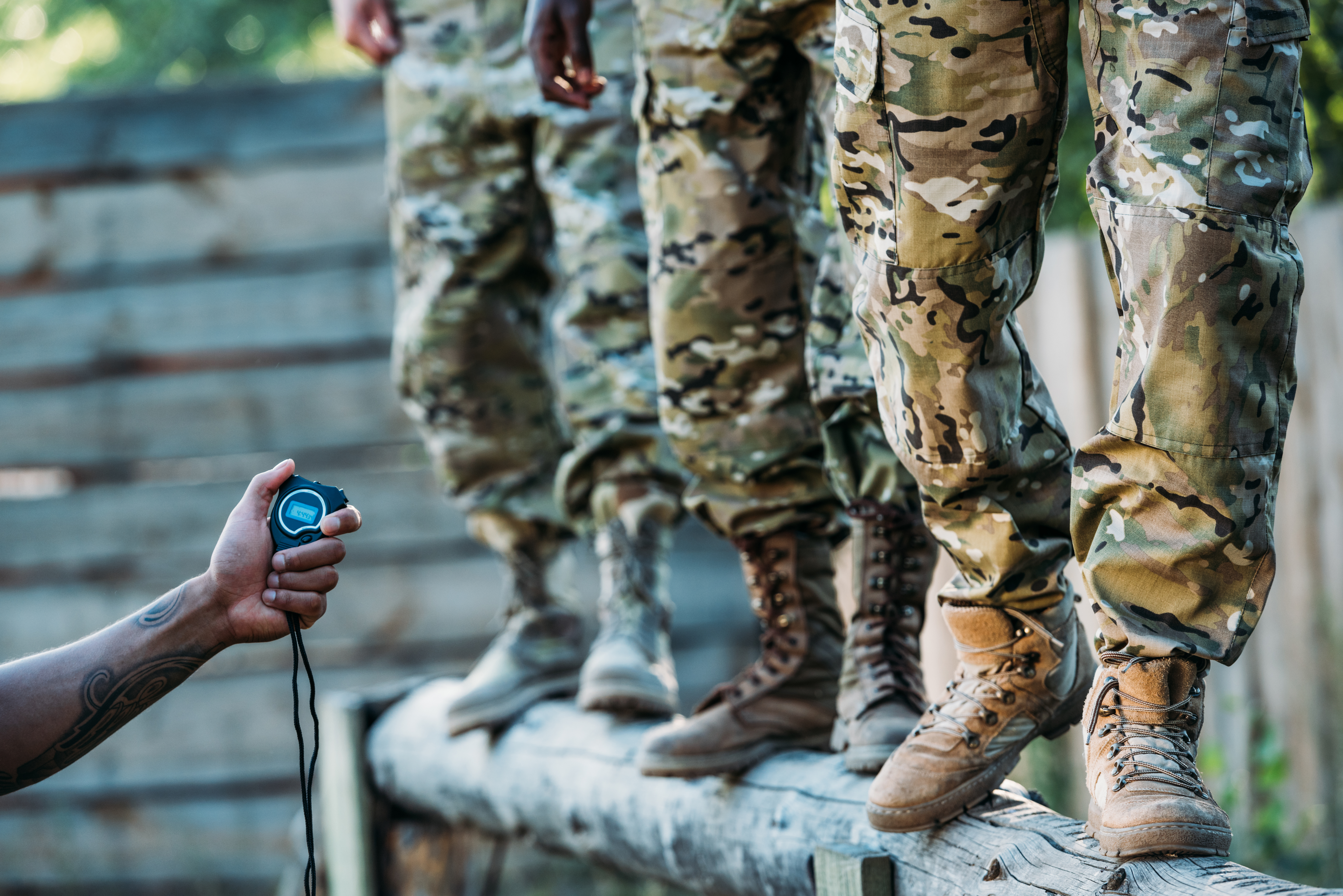 Instructor with stop watch examining soldiers during obstacle